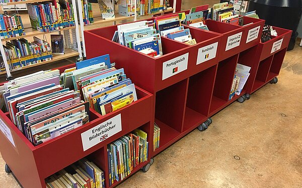 Unsere roten Tröge mit Bilderbüchern auf englisch, rumänisch, portugiesisch, ungarisch und viele mehr.