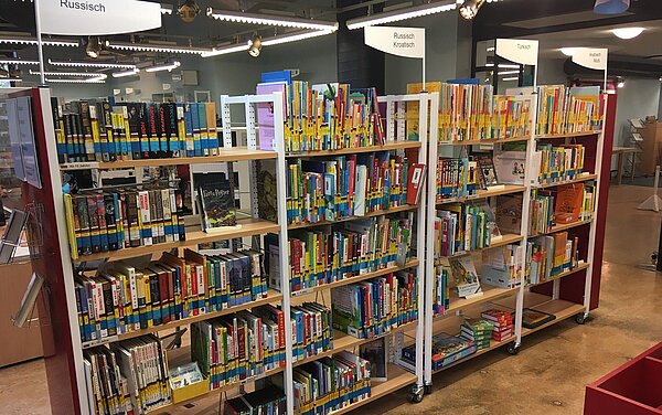 Ein volles Bücherregal in der Kinder- und Jugendbibliothek mit Büchern auf russisch, koratisch, türkisch, arabisch.