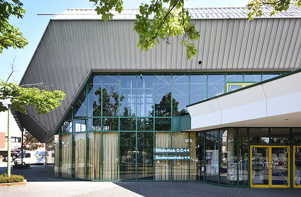 Außenansicht der Badnerlandhalle mit der Beschriftung "Bibliothek" an der Fassade, die zum Bibliothekseingang auf der Rückseite der Halle weist.