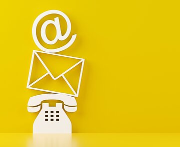 Ein weißes Telefon, darüber ein Briefumschlag, darüber ein at-Zeichen auf gelbem Hintergrund