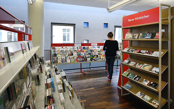 Eine Frau steht vor den Hörbuch-CDs