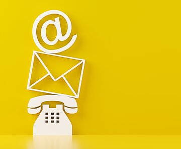 Ein weißes Telefon, darüber ein Briefumschlag, darüber ein at-Zeichen auf gelbem Hintergrund