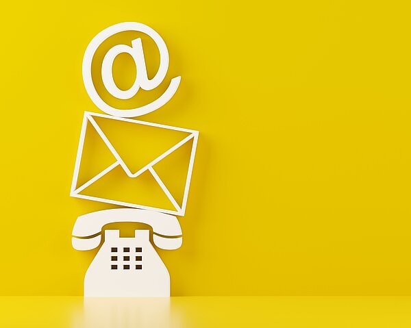 Ein weißes Telefon, darüber ein Briefumschlag, darüber ein at-Zeichen auf gelbem Hintergrund